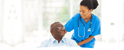 Trinity Care Adult Day Care Center, nursing home — Caregiver assisting a senior man in a bright room