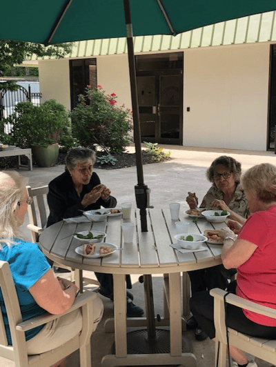 Residents enjoying lunch outdoors at a dining table