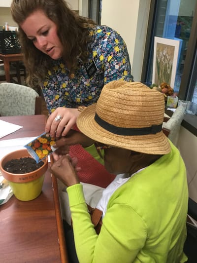Skylark Adh – Johns Creek, home care in Suwanee, GA — Resident planting seeds with staff member's assistance
