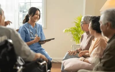 Your Parent’s Place, nursing home — Healthcare professional engaging with seniors in a cozy room