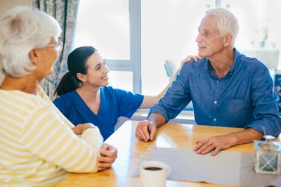 A caregiver speaking with senior residents at a table