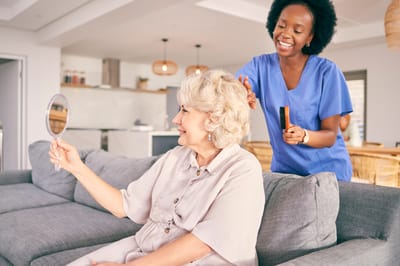 Caregiver styling a resident's hair in a cozy lounge