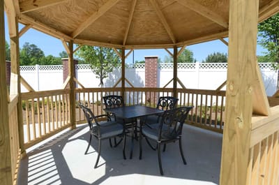 Wooden gazebo with a table and chairs in a garden