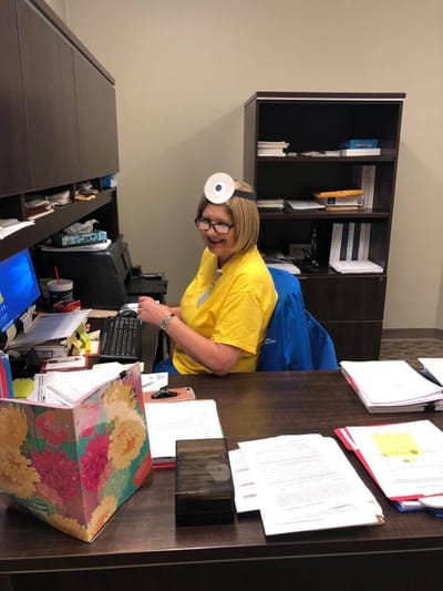 Staff member at a desk with playful demeanor