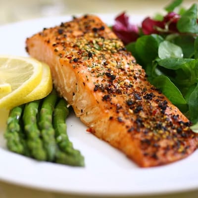 A plate of grilled salmon with asparagus and salad