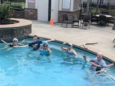 Residents enjoying a pool activity with pool noodles