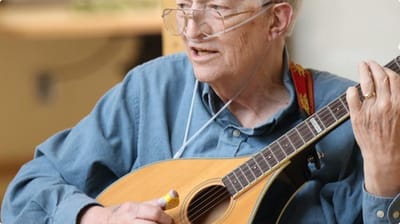 Resident playing a mandolin in a common area