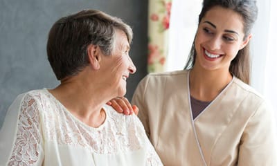 Coastal Manor, Nursing Home in Ludowici, GA — Caregiver interacting with smiling senior resident indoors