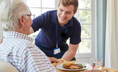 Coastal Manor, Nursing Home in Ludowici, GA — Caregiver serving a meal to an elderly resident