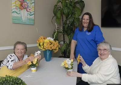 Carrollton Nursing & Rehab Ctr, Nursing Home in Carrollton, GA — Residents arranging flower pots with staff assistance