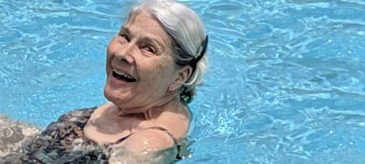 Senior woman smiling while floating in a swimming pool