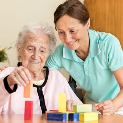A caregiver and resident engaged in a colorful activity