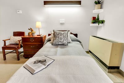 Cozy resident room with bed, chair, and nightstand