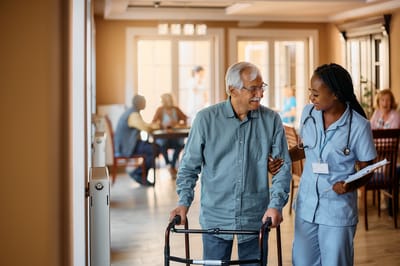 Nurse Care of Buckhead, Nursing Home in Atlanta, GA — Senior resident assisted by nurse in a communal space