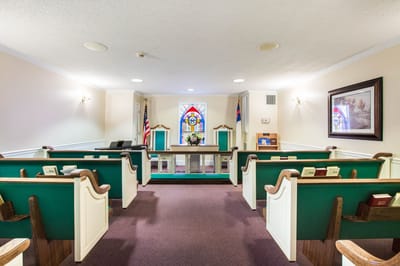 Interior view of a chapel with pews and stained glass