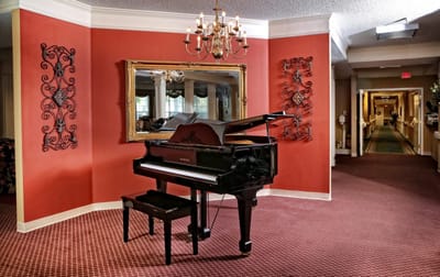 Interior view of a common area with a piano and chandelier