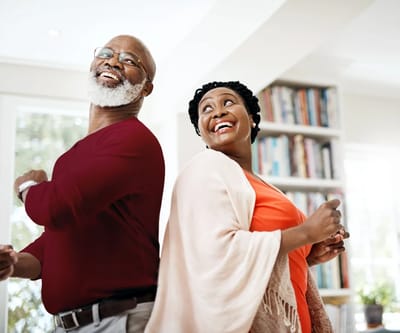 Two seniors smiling and dancing in a bright room
