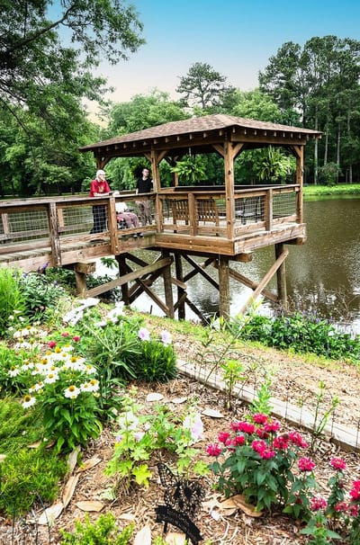 Visitors enjoying a gazebo by a pond with flowers