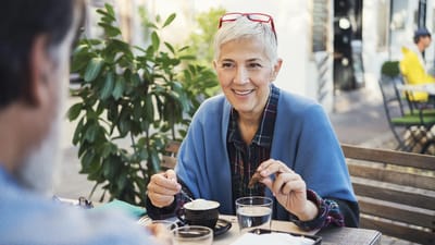 A woman enjoying coffee outdoors with a smile