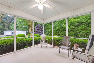 Screened porch area with seating and greenery