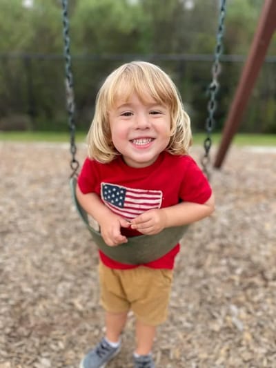 Child smiling while swinging in a playground