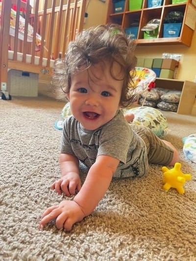 A smiling baby playing on a carpeted floor