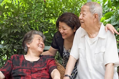Two seniors enjoying time with a caregiver outdoors