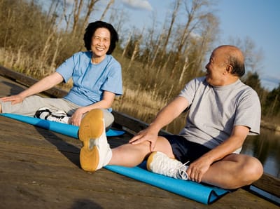 Residents engaging in outdoor stretching exercises by a lake