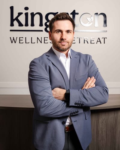 Staff member posing in front of the facility's logo