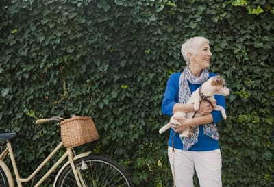 Woman with a small dog near a bicycle in a garden