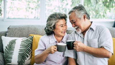 Two smiling residents sharing coffee on a couch