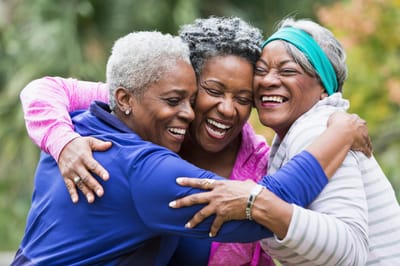 Three women joyfully embracing outdoors