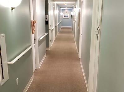 A hallway inside a senior care facility with light blue walls