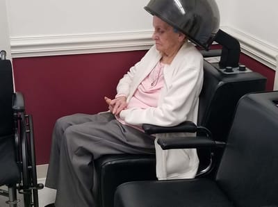 Senior resident enjoying a hair treatment in a salon chair