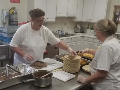 Two staff members preparing food in the kitchen