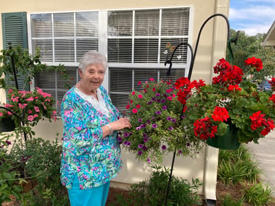 Resident tending to hanging flowers in a garden area