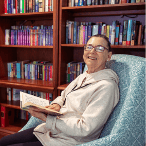 The Gardens at Calvary Alc, assisted living in Columbus, GA — Senior resident reading a book in a cozy library