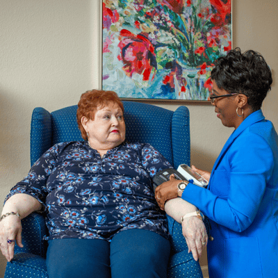 The Gardens at Calvary Alc, assisted living in Columbus, GA — Caregiver assisting resident in a comfortable sitting area