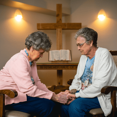 Two residents holding hands in a thoughtful moment