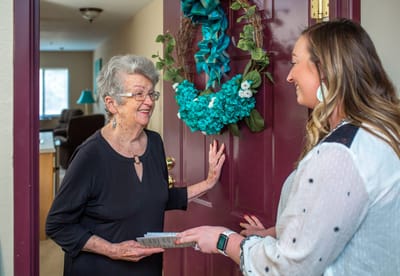 A staff member greeting a resident at their door