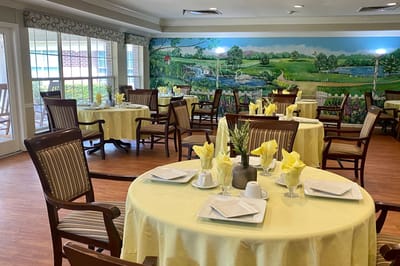 Dining room setup with yellow tablecloths and floral mural