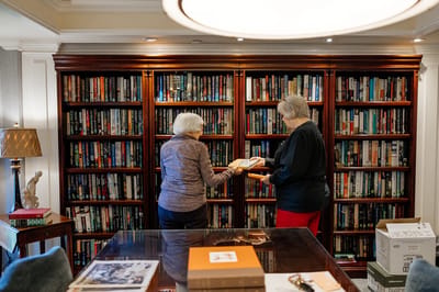 Two residents browsing books in a cozy library