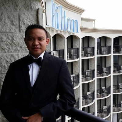 A man in a tuxedo posing on a balcony with a hotel sign