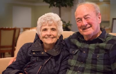 Two smiling residents sitting together on a couch