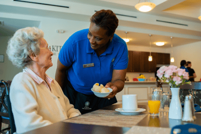 Staff serving food to a resident in a dining area