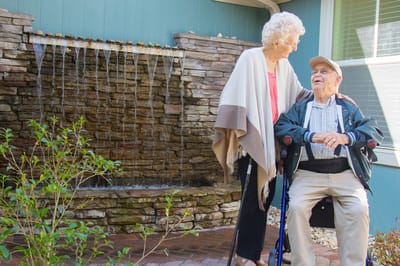 Resident and staff member by a water feature