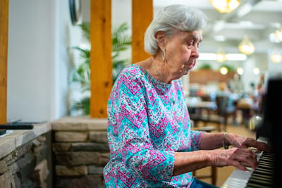 Resident playing piano in a common area