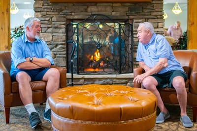 Two residents chatting by a cozy fireplace
