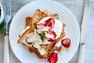 Plate of French toast topped with strawberries and cream