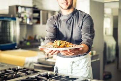 Chef presenting a gourmet meal in a kitchen